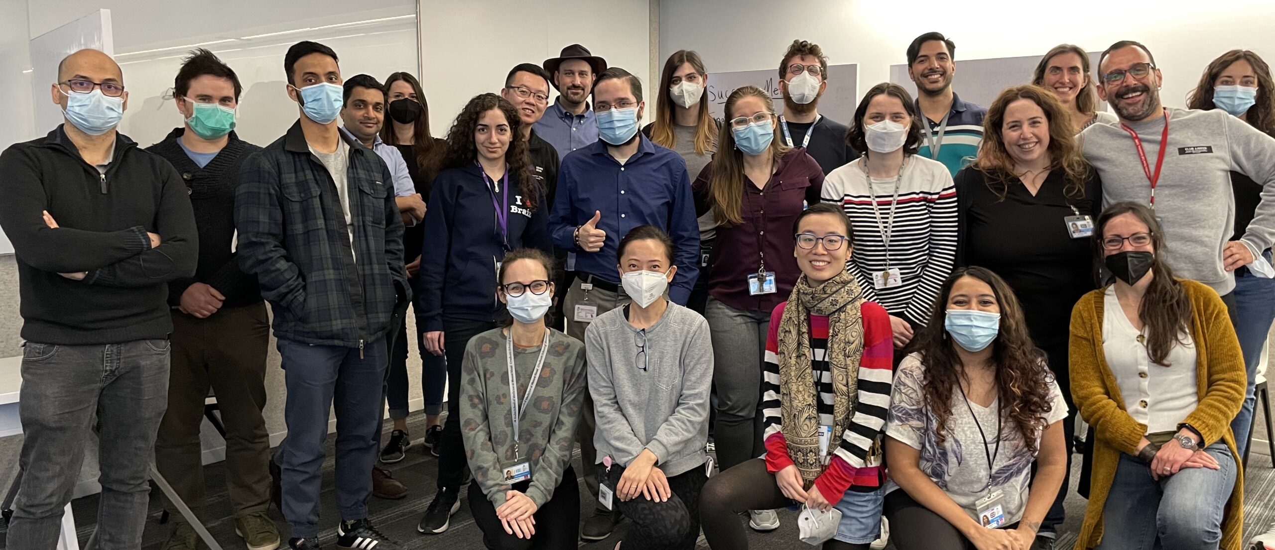 A large group of Mount Sinai postdocs who are joining together to form a union are standing side by side looking at the camera. Many are wearing masks.